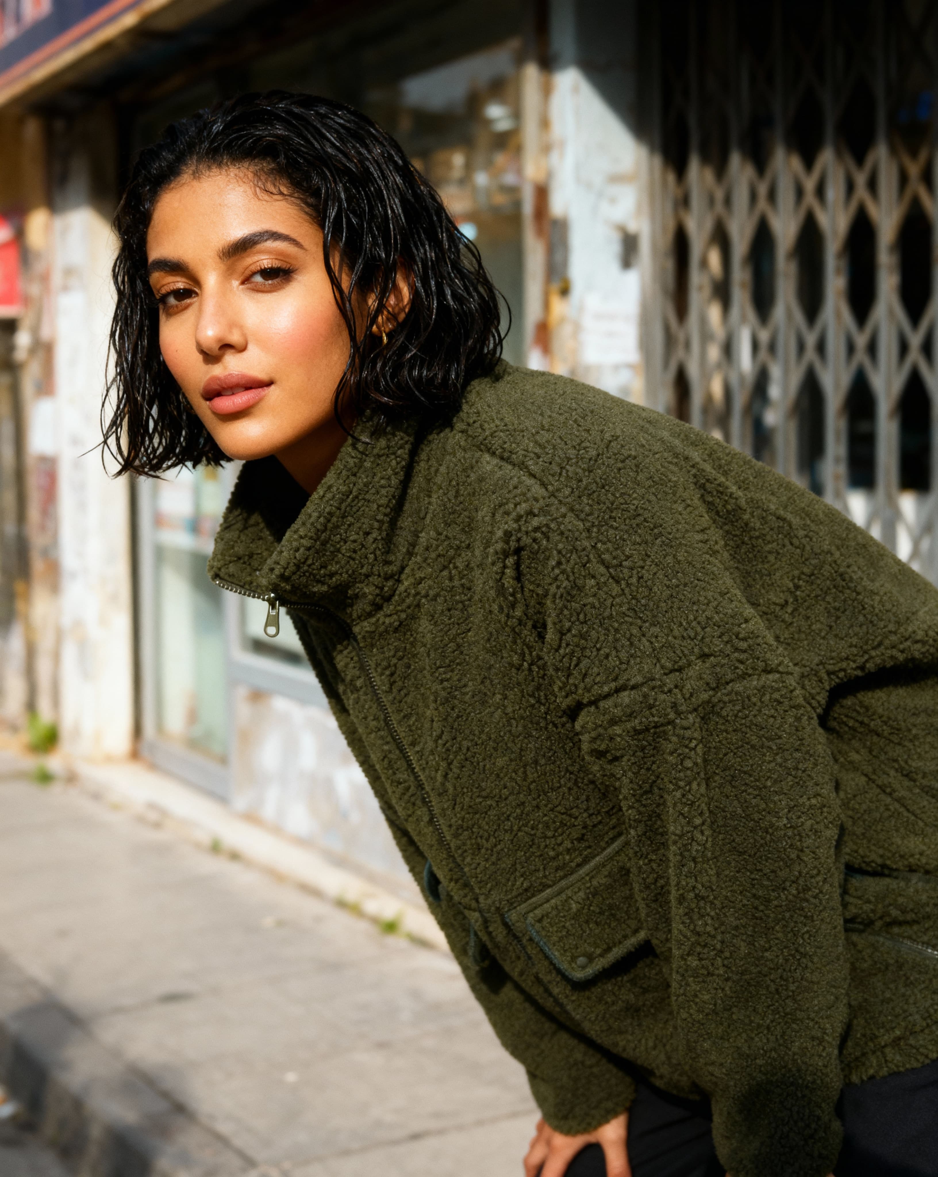 Egyptian woman in olive fleece jacket on urban street, detected by also works